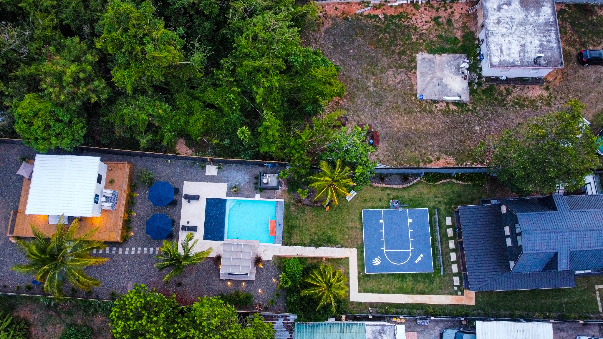 Vista aérea vertical de una propiedad tropical con piscina y cancha